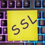 Certyfikat bezpieczeństwa SSL napisany na żółtej naklejce na klawiaturze laptopa z oświetleniem tylnym.